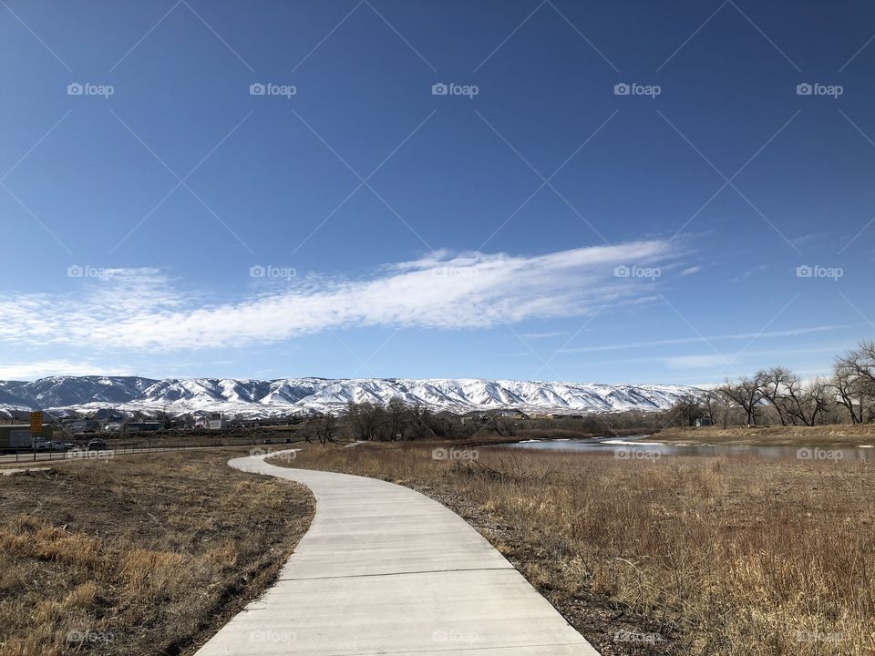 Walking path with blue sky and snowy mountains in the background. 