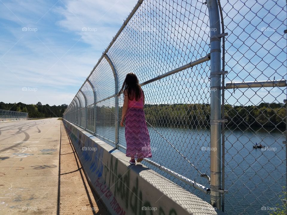 Rear view of a girl walking on surrounding wall