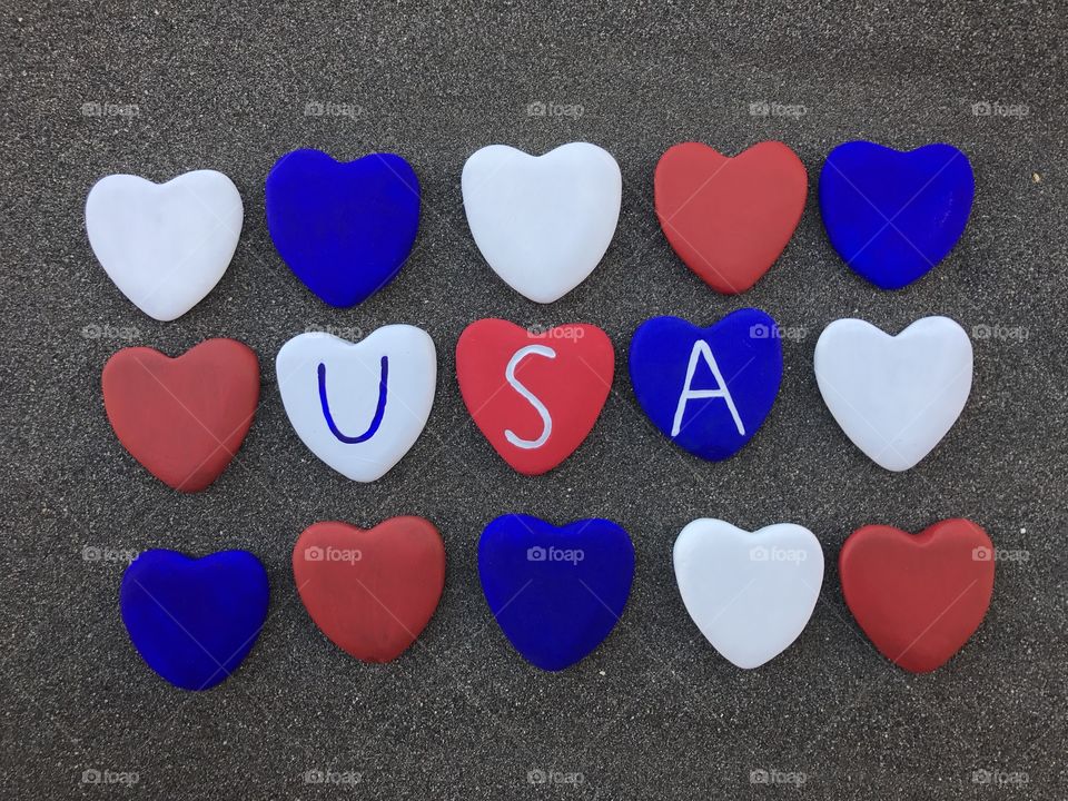 United States of America with colored heart stones over black volcanic sand