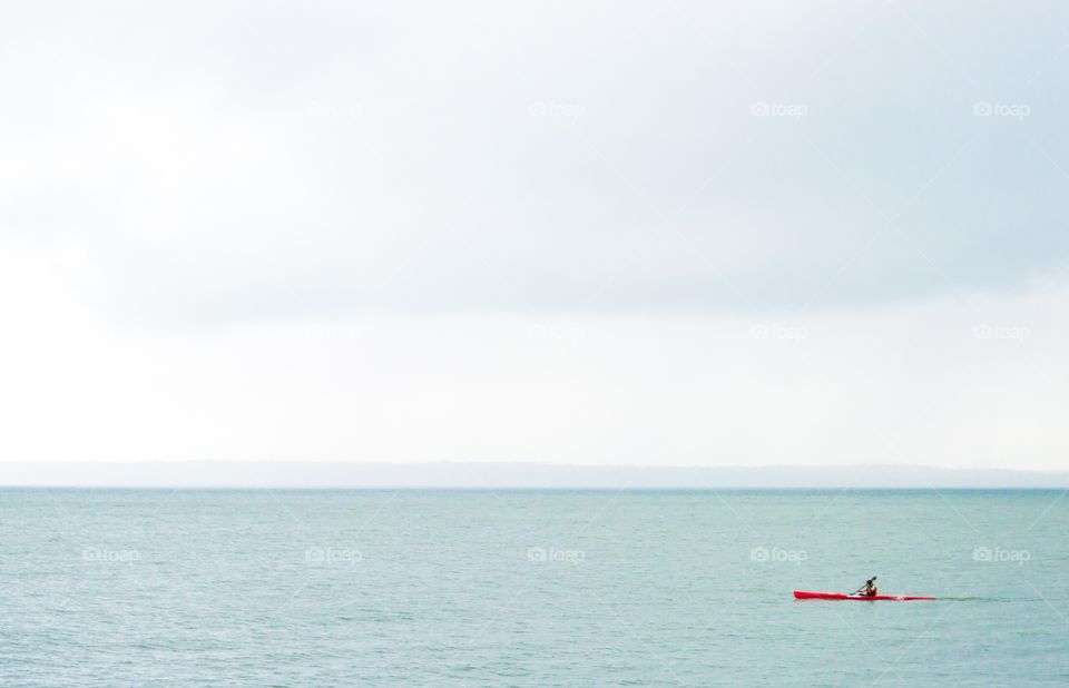 Kayaker on the bay. Kayaker in a red kayak on the green water