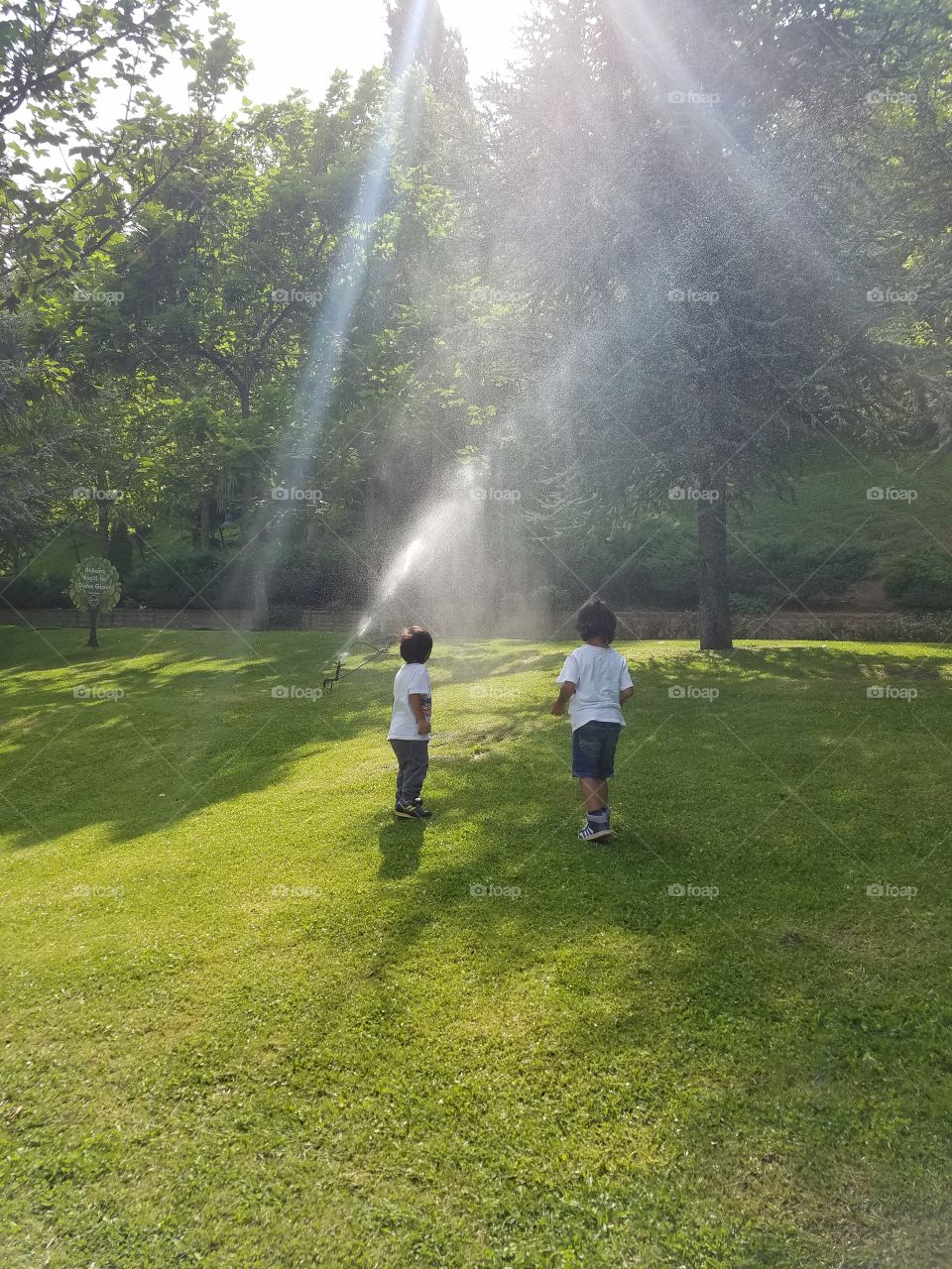 children playing in a sprinkler system in the grass of the dikman vadesi park in Ankara Turkey