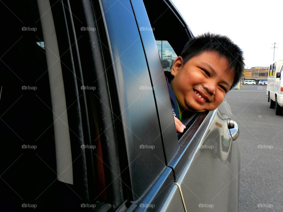 young boy peeking out a car window