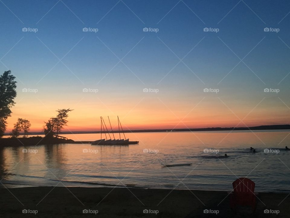 Beautiful lake, boats, and swimmers during sunset in summertime 