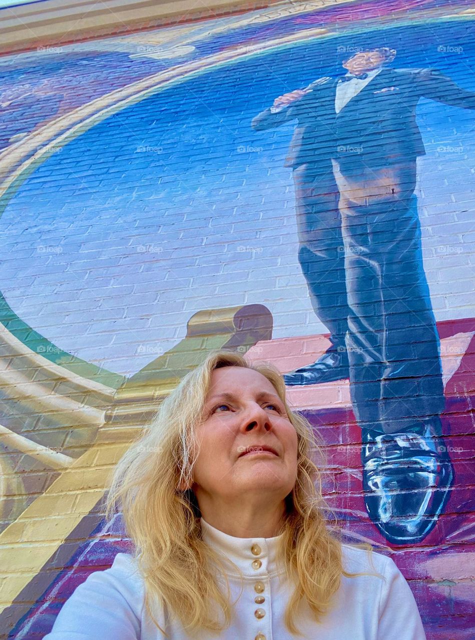 Woman standing by a man’s shoes in street art