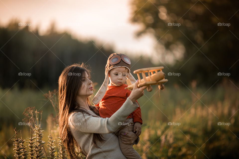 Mother and son with wooden plane at sunset