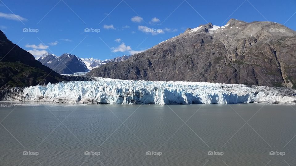 Icy Glacier Bay view of glacier and mountains and ocean on sunny day from cruise ship in Alaska