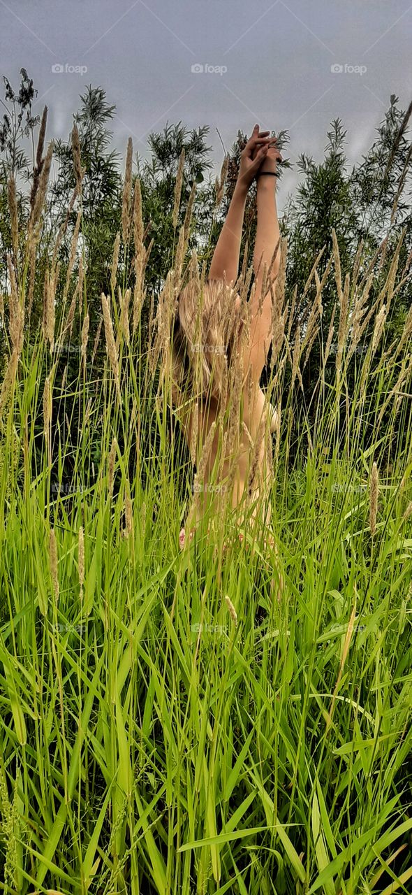 девушка стоит спиной в высокой траве