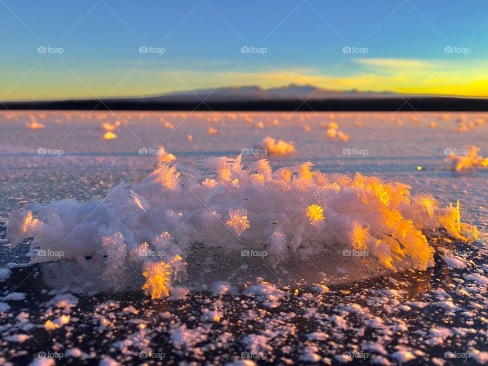 Frost chunks on freezing lake with the sun setting on the mountains. Absolutely stunning lakeside living. 