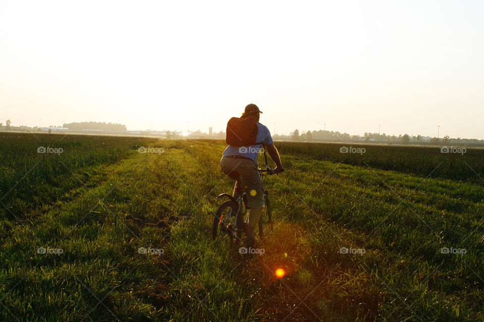 A bicyclist on the field, sunset 