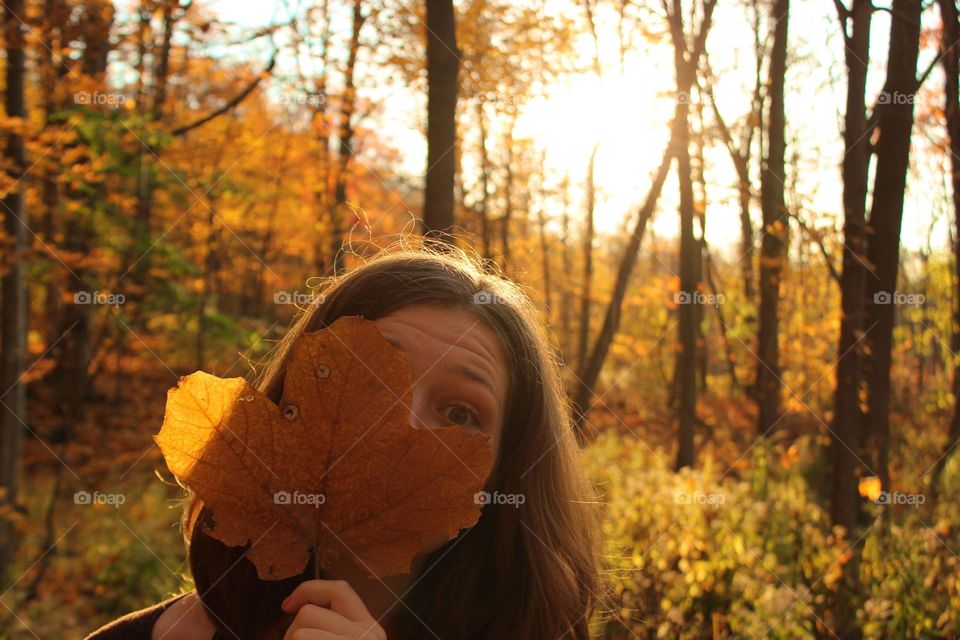 Young woman playing with leaf in autumn