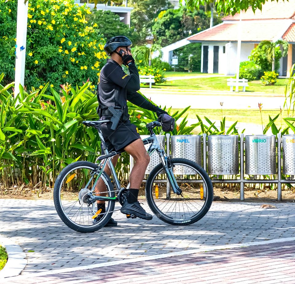 A police officer on a bicycle answers a phone call