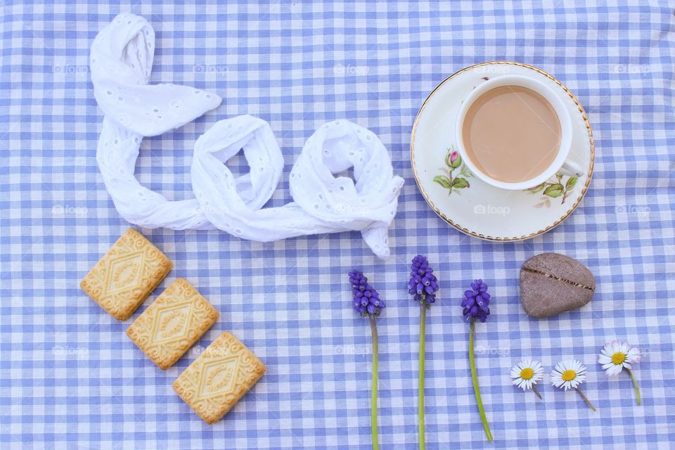 A British cup of tea with a Union Jack and biscuits on a gingham table cloth 