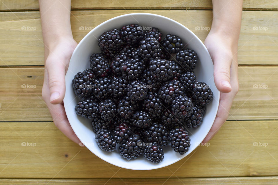 Person holding a bowl of blackberry