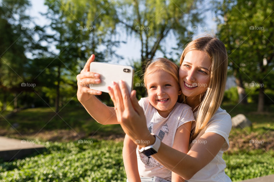 Happy mother and daughter making selfie outdoor
