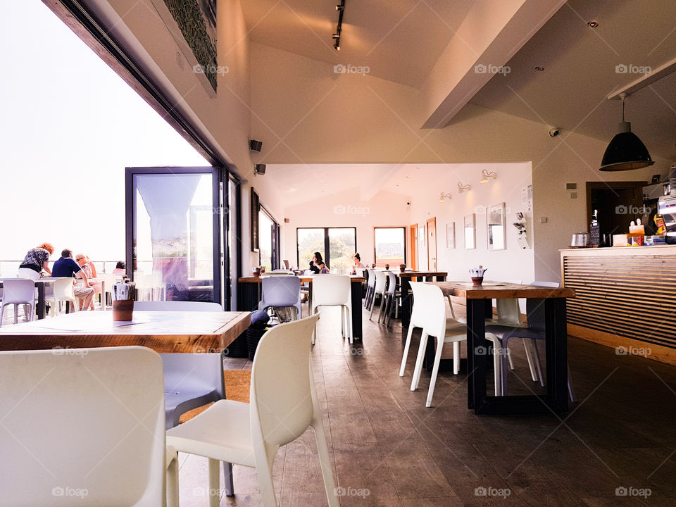 Empty coffee shop with chairs and tables and open balcony.