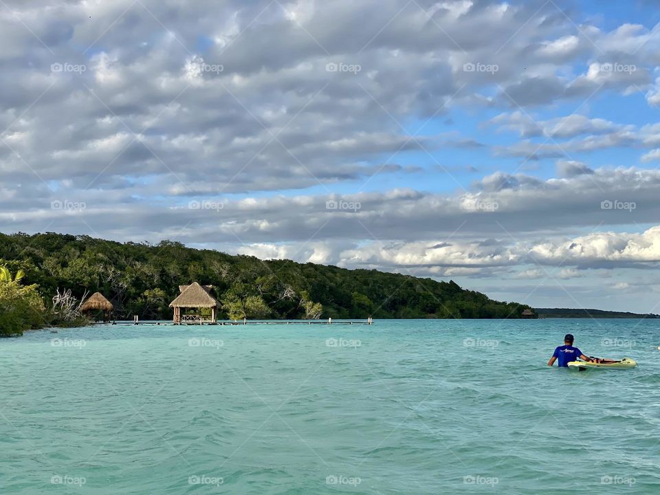 A person next to a paddleboard in a lagoon