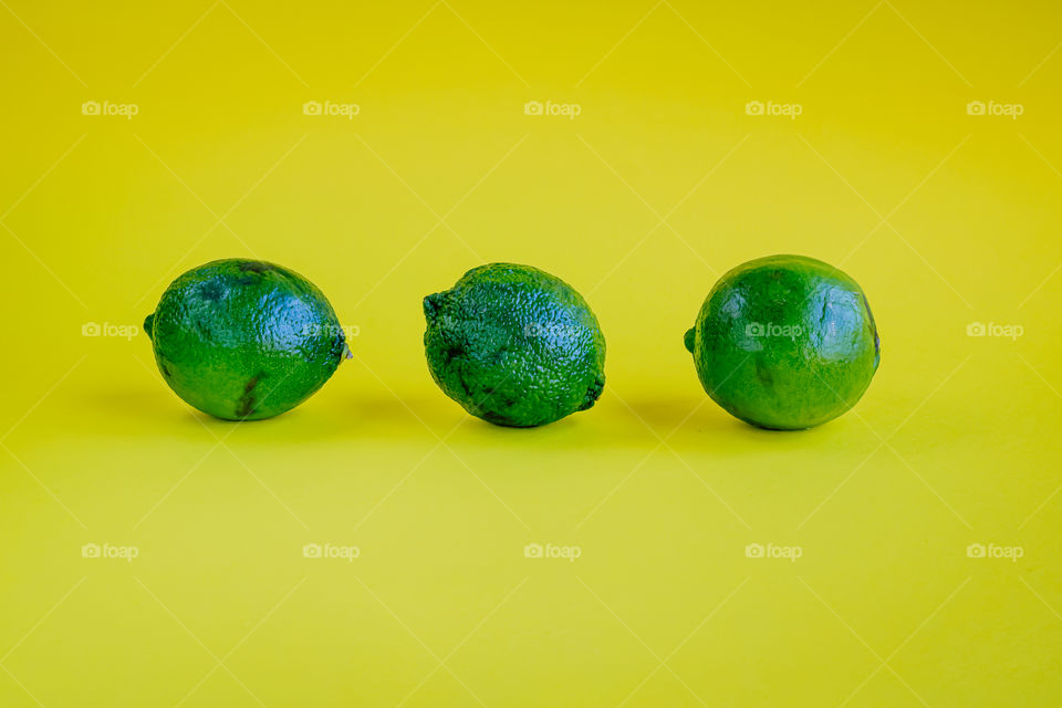 Three limes on a yellow background.