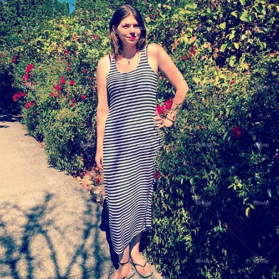 Me standing in a striped dress by the roses.