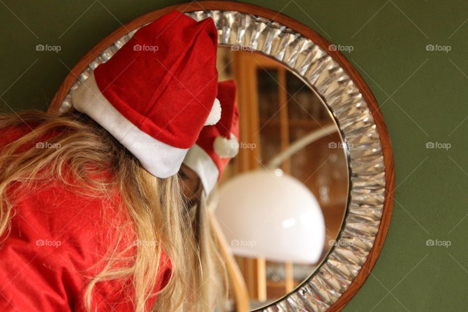 Close-up of a woman dressed up as Santa Claus and reflection in a mirror 