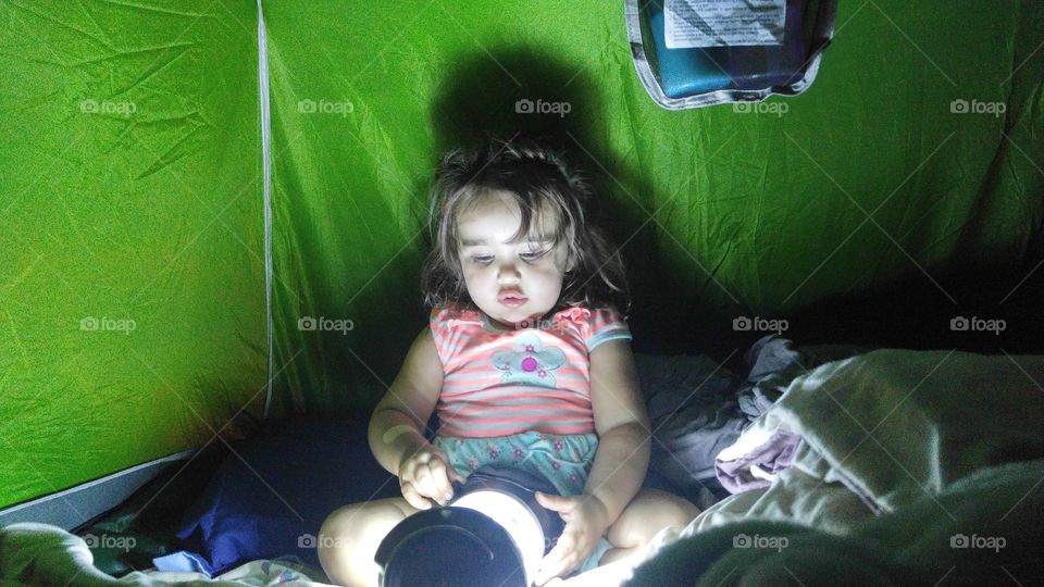 Little girl playing with lantern in tent