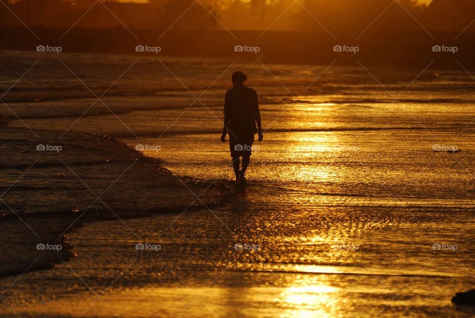 Man walking on beach at sunrise in Guyana