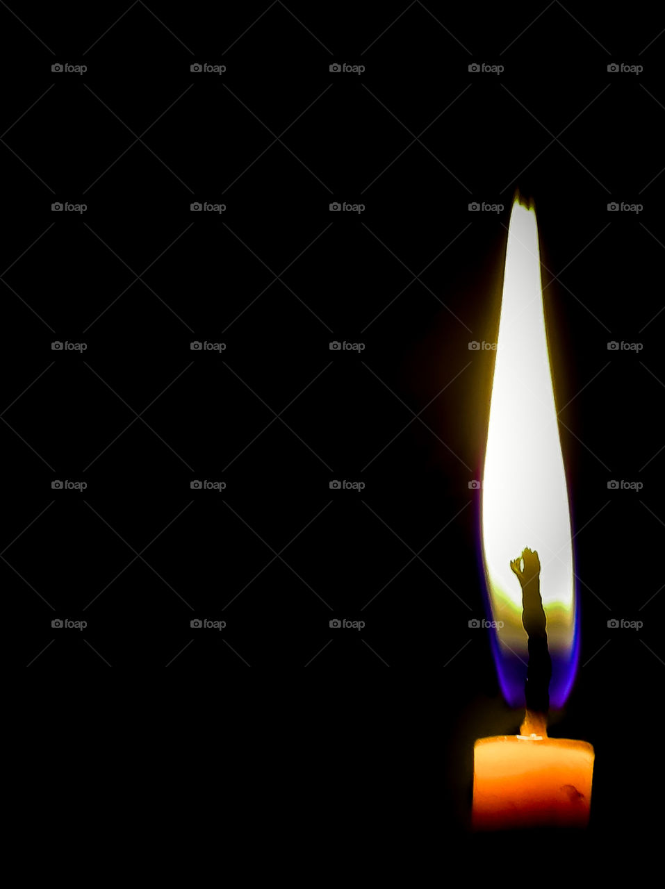 A burning candle on a black background in a frame