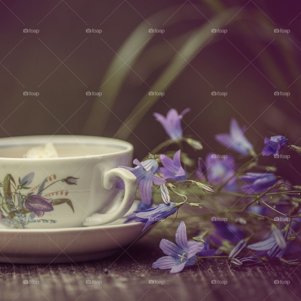 Vintage cup if herbal tea and bouquet of bell flowers 