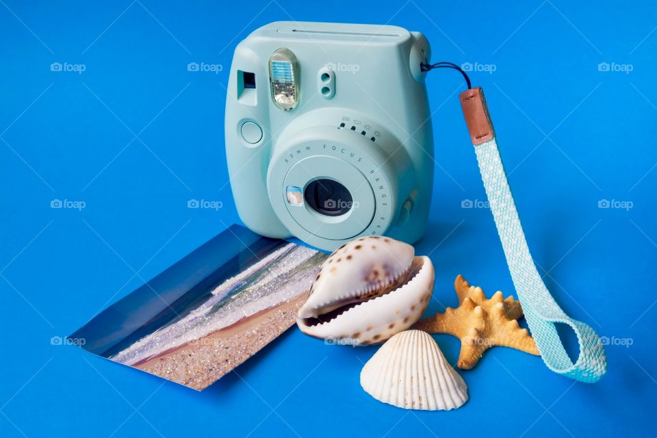 Concept for summer, vacation,travel. Shells, postcard of beach and camera on blue background