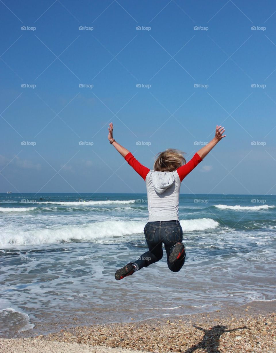 Beautiful summer day! The woman is happy to meet the sea. The jump...