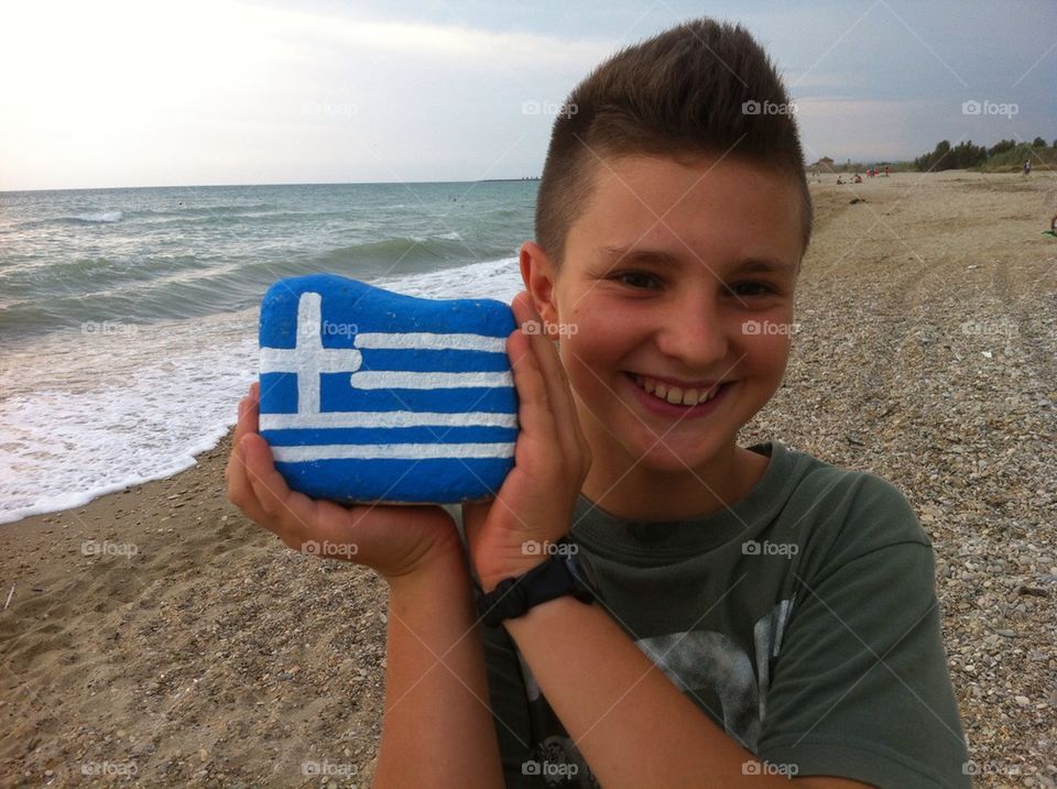 Greece my love, young boy with the national flag on a stone