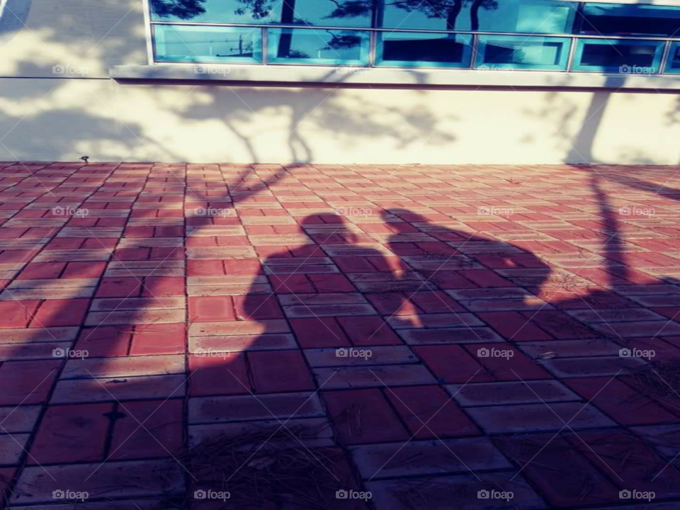 a shadow of a mother who's  sitting while the her child standing  beside her.