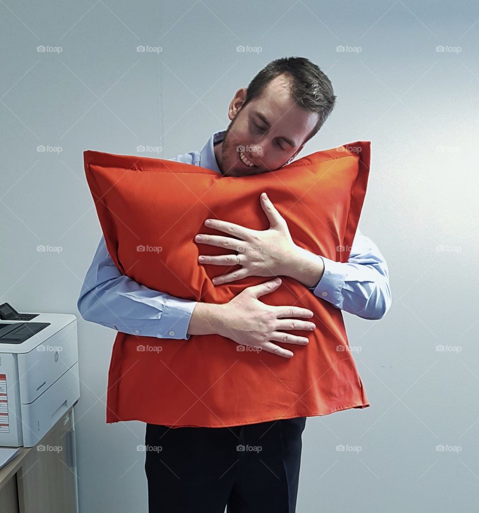 young man office worker huging huge red pillow