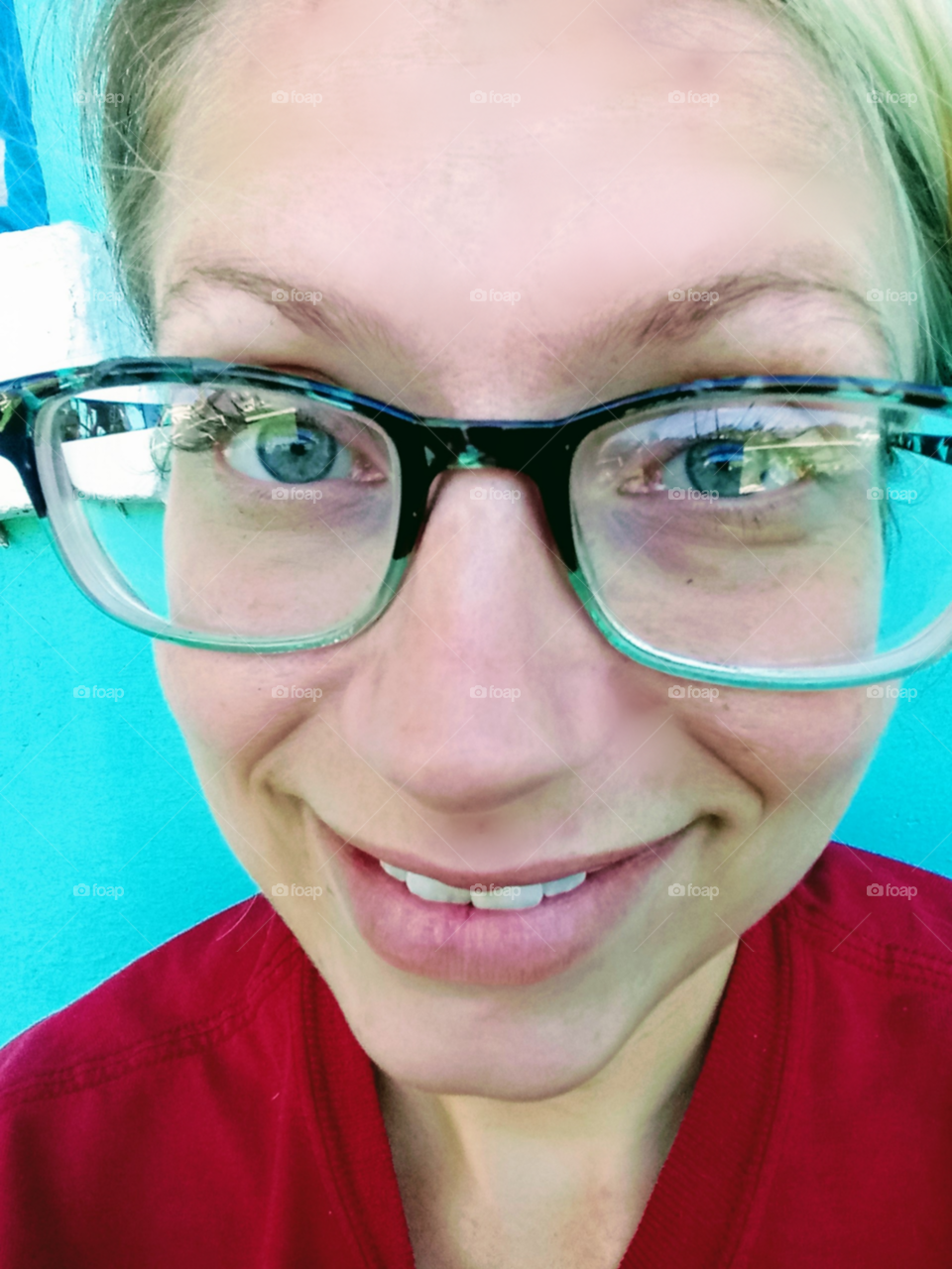 pretty woman wearing glass smiling against a blue wall