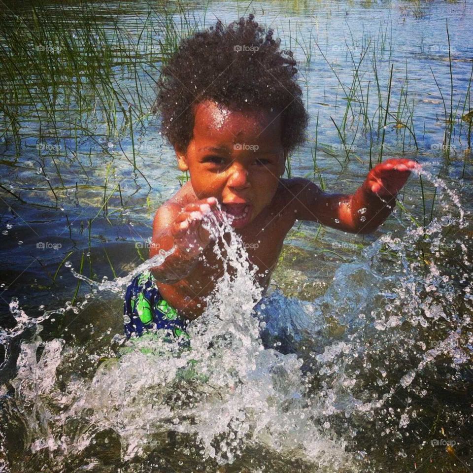 toddler playing in lake splashing