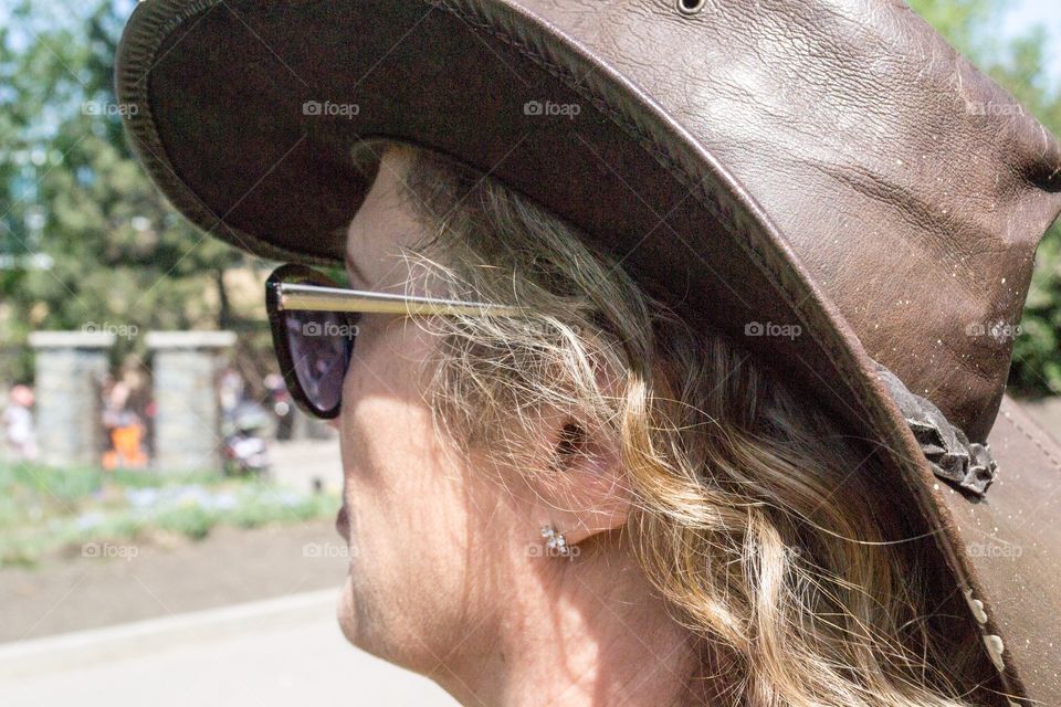 Middle aged blond woman wearing leather cowboy hat and sunglasses sunnies