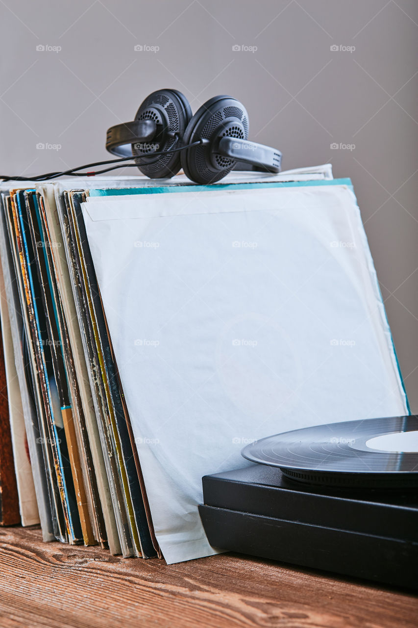 Stack of many black vinyl records, turntable vinyl player and headphones put on the stack. Classic stereo set. Candid people, real moments, authentic situations