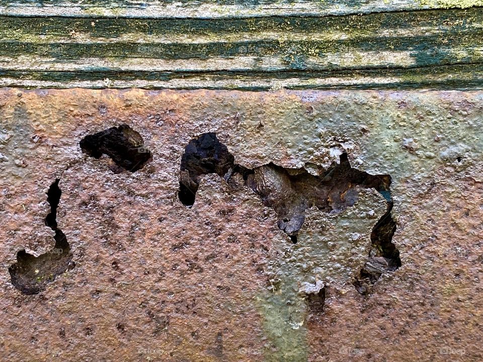 A piece of rusty metal and some weathered wood from a piece of old farm equipment