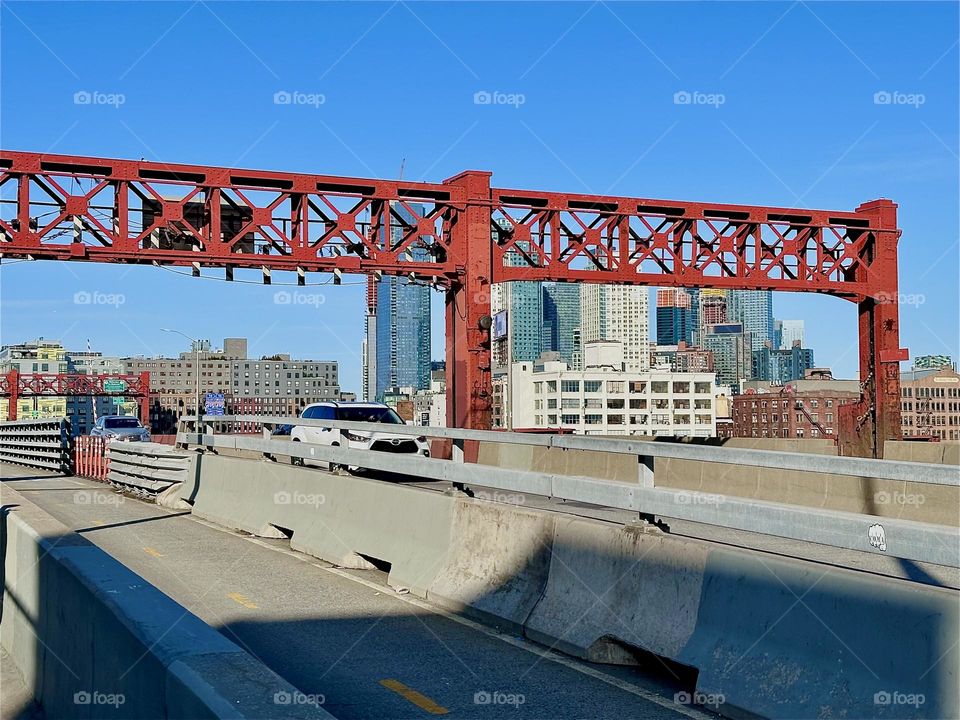 These are the pedestrian and bicycle lanes of the „Pulaski Bridge“ at „Newtown Creek“ that connects „Greenpoint“, Brooklyn to LIC, Queens. The red metal ornamented gate ties in with other metal structures in red. 2024. Hypnotic Productions