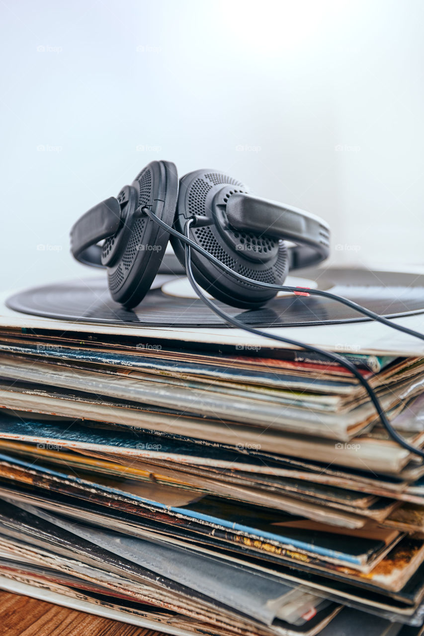 Stack of many black vinyl records and headphones put on the stack. Classic stereo set. Candid people, real moments, authentic situations