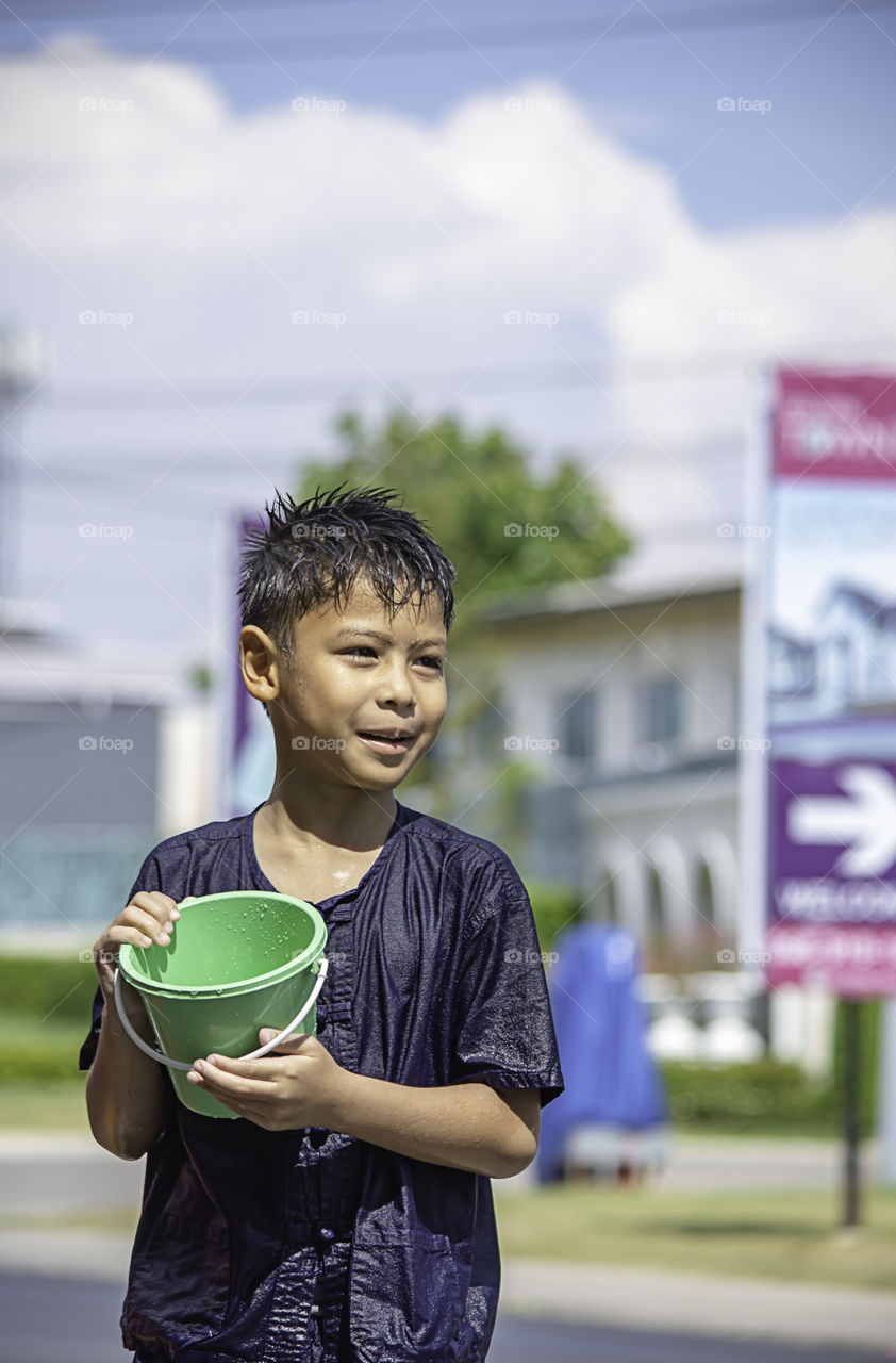 Asian boy holding Plastic bucket play Songkran festival or Thai new year in Thailand.