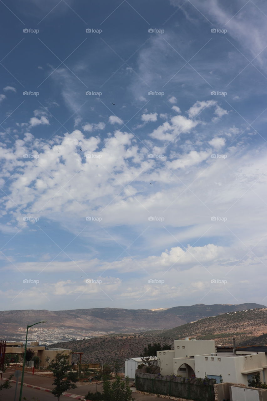 Blue sky, white clouds, mountains and a pack of birds 