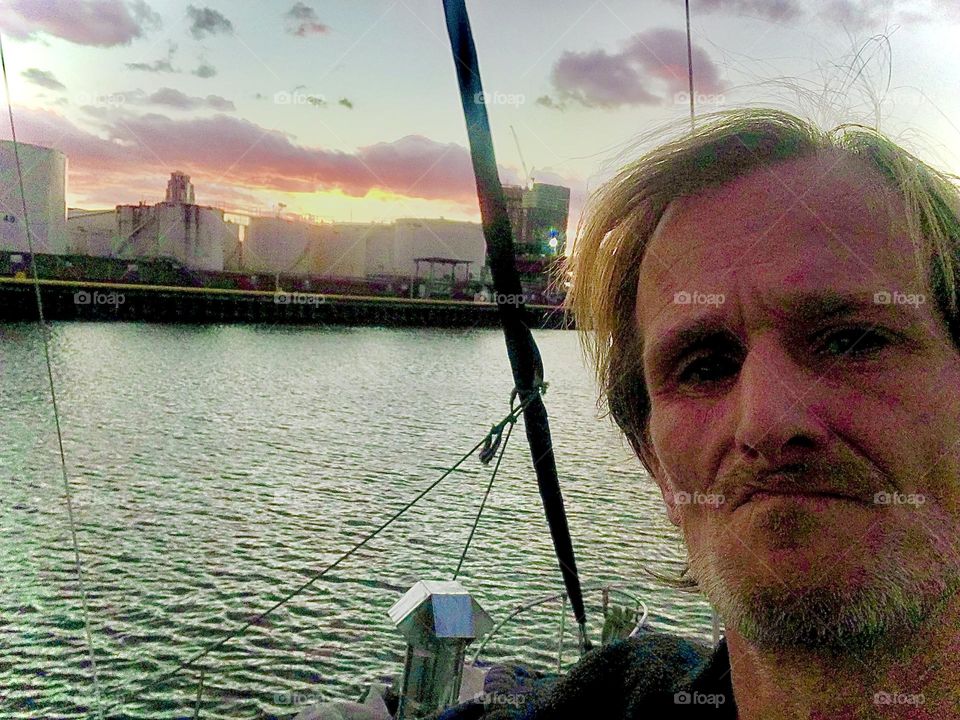 Timothy Trespas aboard our sailboat, the „Salvation“ standing on the front deck photographed on a late afternoon in 2018 against the backdrop of the Greenpoint, Brooklyn side of the shore. Hypnotic Productions