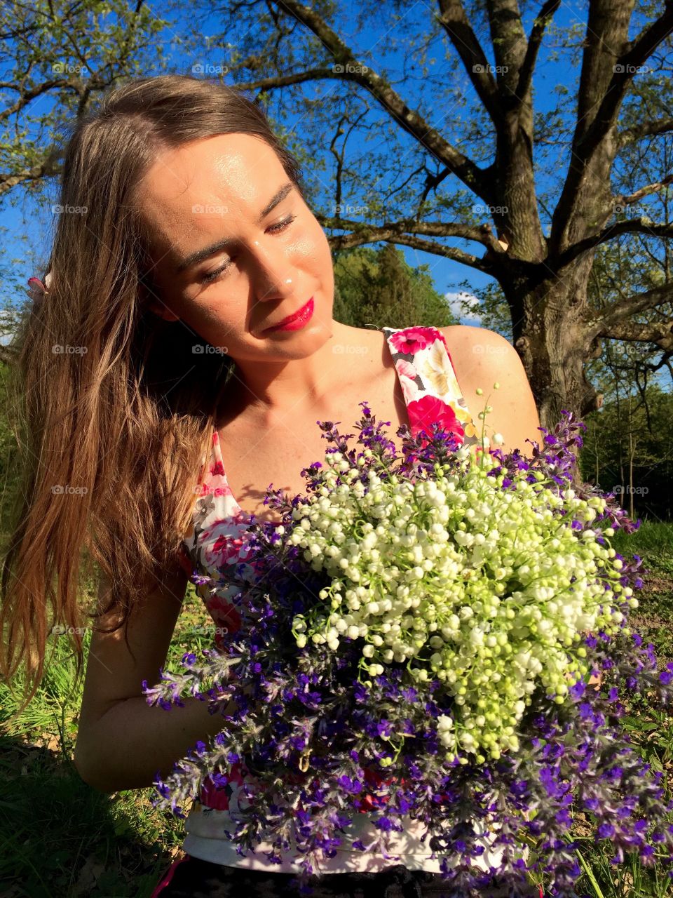 MPretty young woman holding a bouquet made of purple flowers and lily of the valley