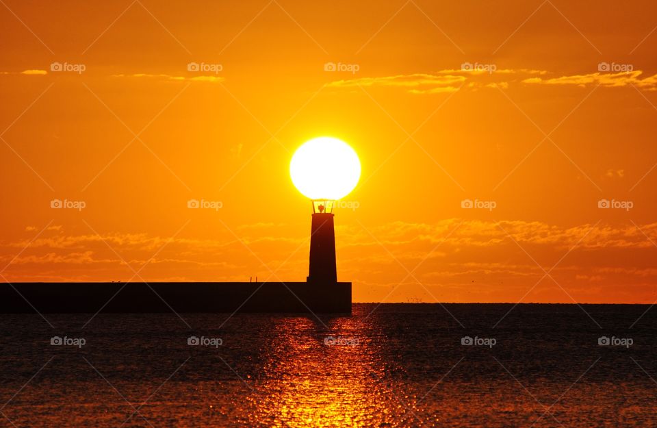 sun above lighthouse during sunrise over the baltic sea in Gdynia, Poland