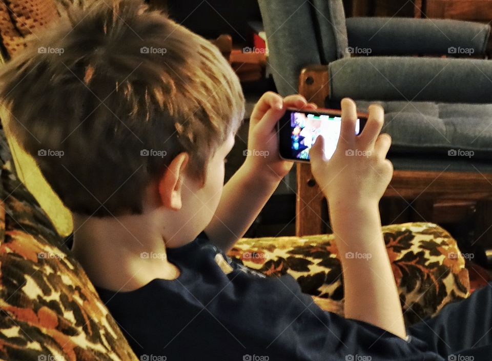 Young Boy Playing On A Smartphone
