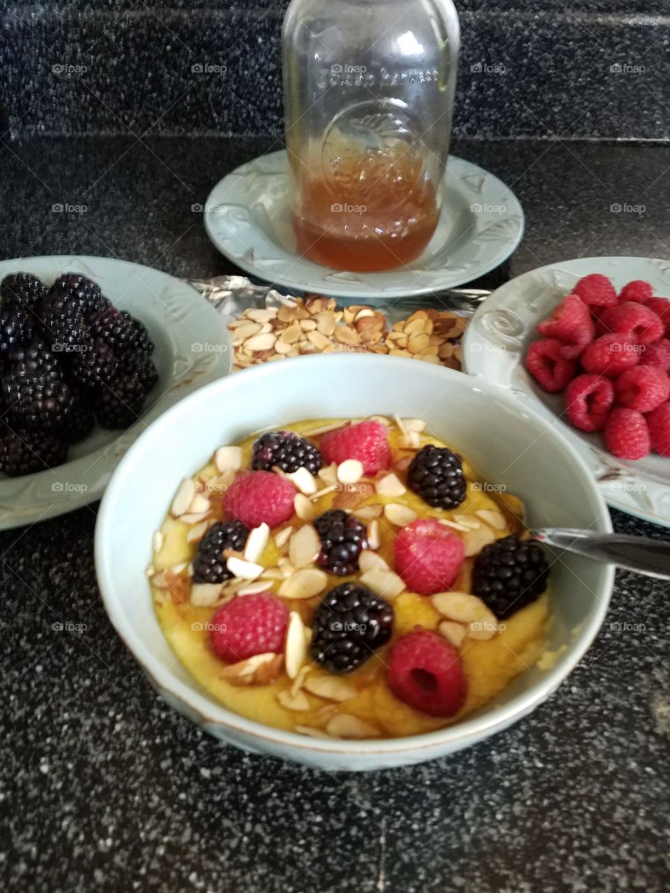 Healthy breakfast.  coarsely ground polenta with raspberries,blackberries, toasted almond slices and fresh honey.