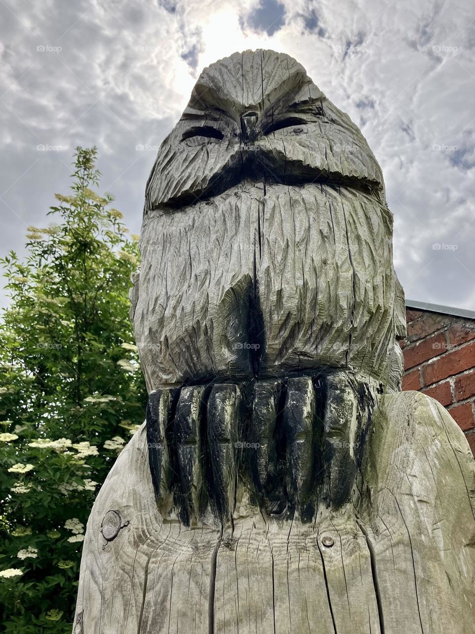 A wood carving of an owl on top of a tall tree stump 