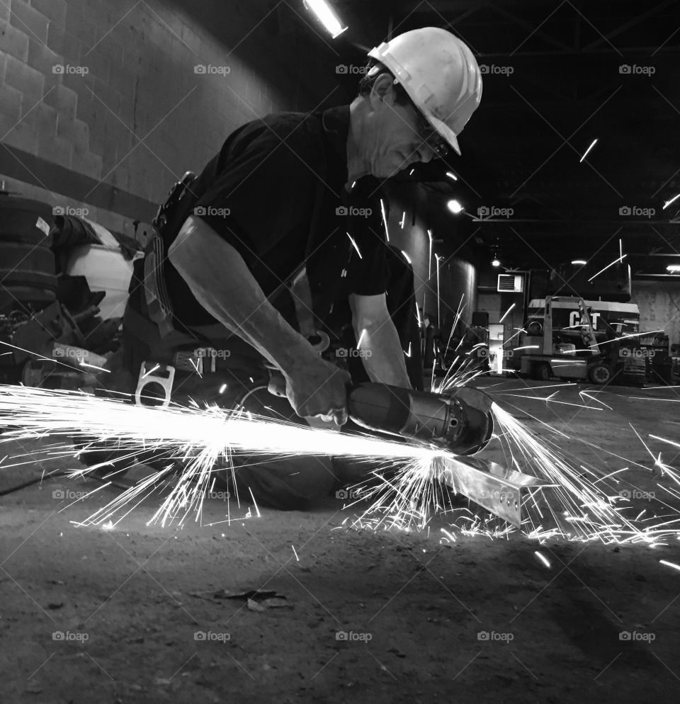 Welder grinding metal in workshop