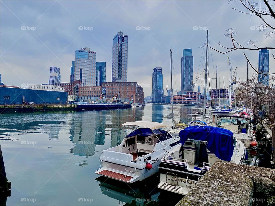 The boats at “Newtown Creek” closeup right on the LIC shore, “Greenpoint”, Bklyn across the water left and the “Manhattan” skyline in the far distance makes for a wonderful overall view. 2023. Hypnotic Productions