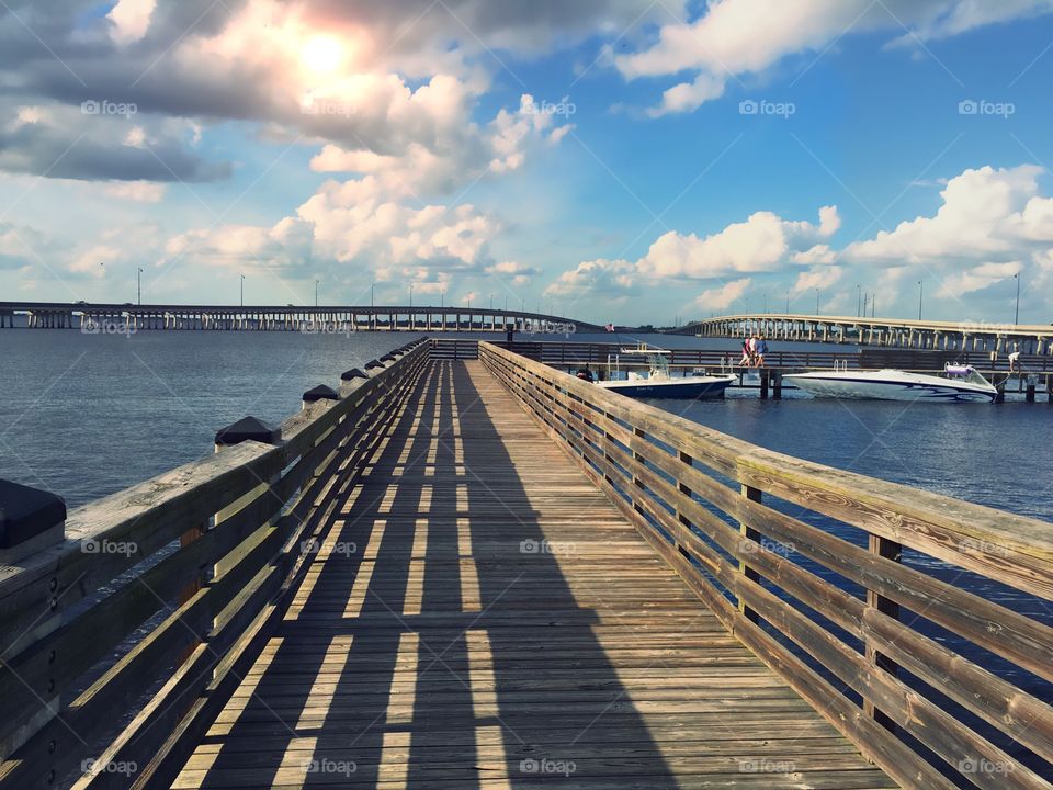 Long pier over the water on a bright , beautiful sunny day casting shadow and light in symmetrical lines.